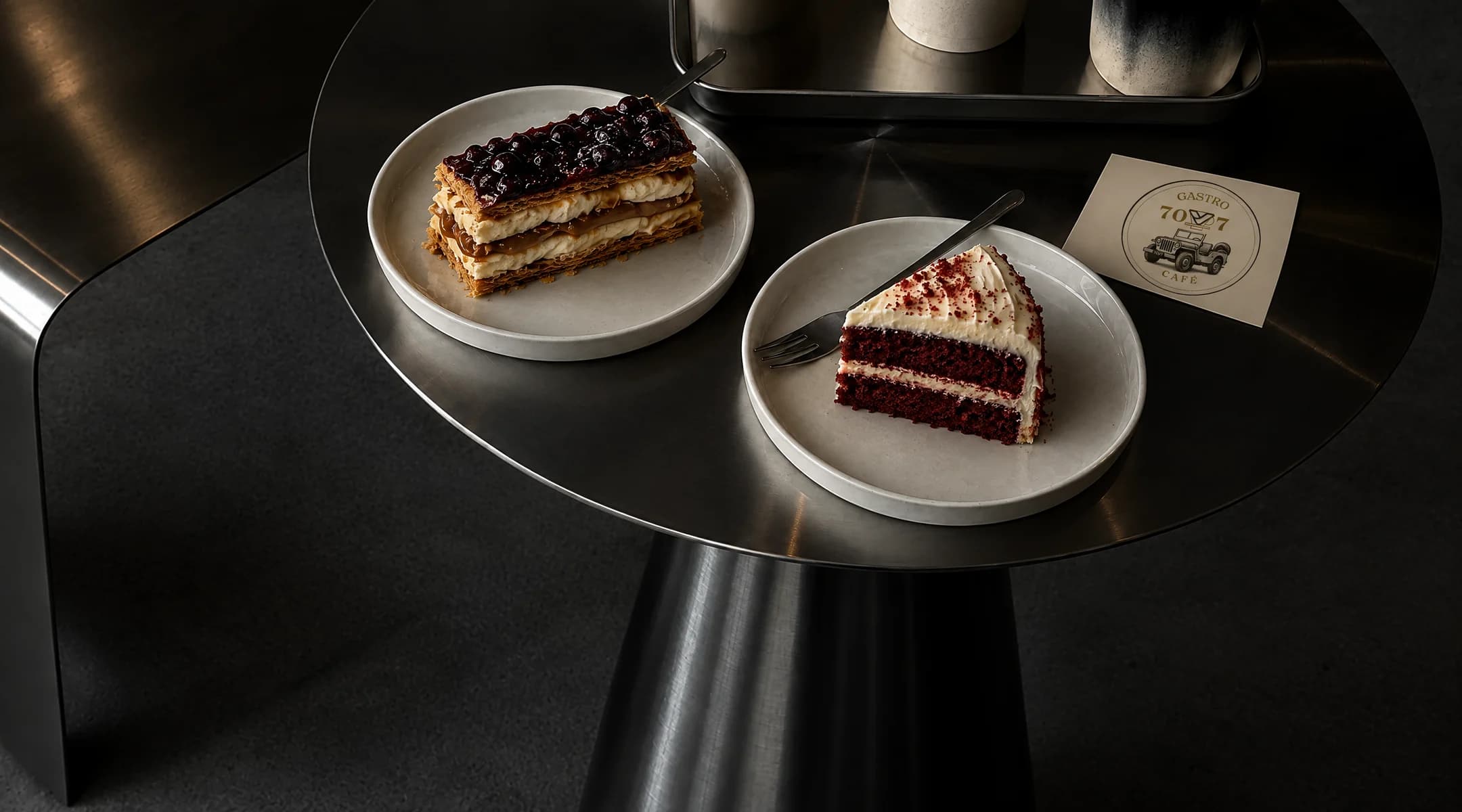 Una milhoja y una torta red velvet sobre una mesa de acero, junto a una tarjeta de Gastro 70V7